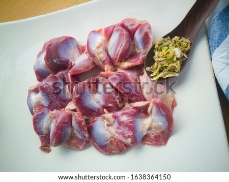 Close-up pictures of chicken gizzard with spices Pound crushed garlic and pepper for marinating on a plate of garlic.
