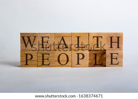 Wooden cubes with lettering spelling Wealth People. Business or political concept asking if wealth comes above people