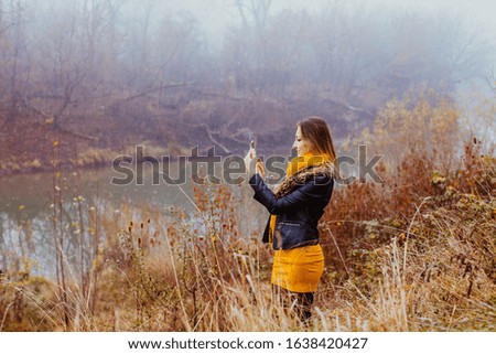 Glamorous woman making selfie outdoors in autumn. Pretty stylish girl taking picture with mobile phone.