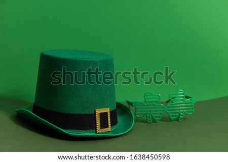 Happy St Patricks Day. Lepricon hat with glasses in the shape of a three leaf clover on a green background. Holiday attributes