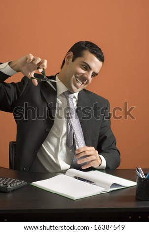 Crazy businessman about to cut his tie off. Vertically framed photo.