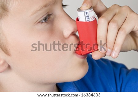 Asthma inhaler being used by boy in blue shirt Royalty-Free Stock Photo #16384603