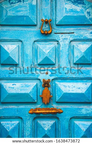Close up on Old wooden turquoise entrance rdoor with old stylish door handle in Essaouira, Morroco. Architectural textured background