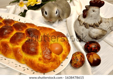 Easter braided brioche with an egg and Easter hen, rabbit and Easter eggs in background