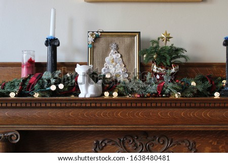 Christmas decor on the mantel with candles, evergreen sprigs and lights.