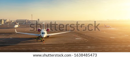 Colorful scenic dramatic morning sunset at airfield asphalt taxiway and parking with different commercial passenger airplanes and private jets ready for departure. Flight tickets booking and charter. Royalty-Free Stock Photo #1638485473