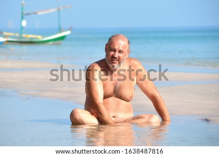 man lying in the puddle. Fat man on the beach. Resort funny pictures. A quiet holiday at the seaside. A man sits in a puddle. Mud bath