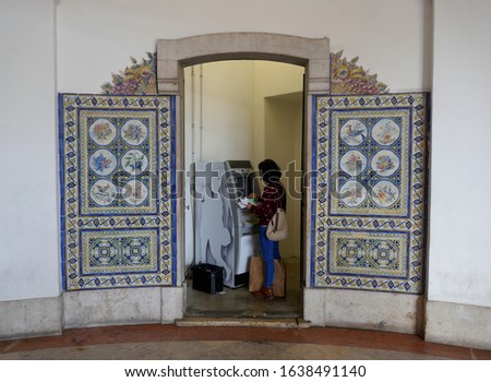 Young woman with black hair using an ATM
to print bank statements and withdraw money. Lisbon, Portugal, Europe.