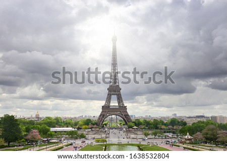 Paris, France. Panoramic image of Eiffel tower with dramatic sky grey clouds with sun beams. This symmetrical picture was taken from the axis of fountains of Trocadero in Spring.