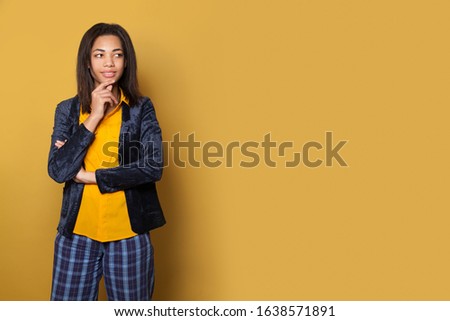 Smart black woman student thinking on yellow background with copy space