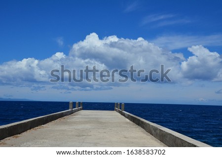 Concrete pier with a blue wavy sea