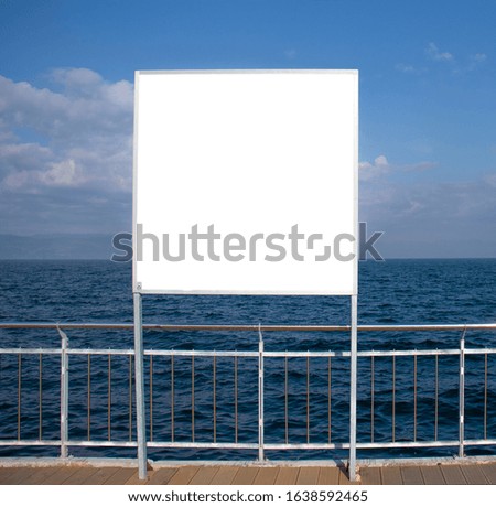 Blank billboard on a background of blue sea and cloudy sky for advertisement. Billboard with place for your text or advertising.