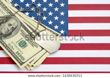 Army identification medallions and dollar bills on United states flag. Military pension, salary in the army or military insurance Royalty-Free Stock Photo #1638630313