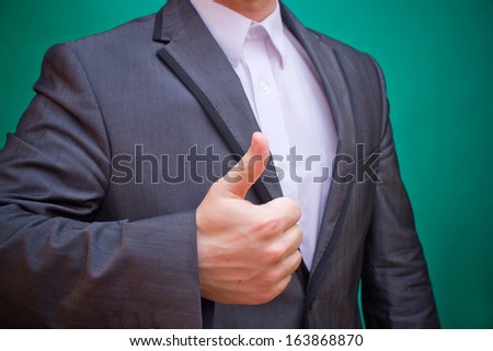 Businessman on a green background showing thumb up sign of success
