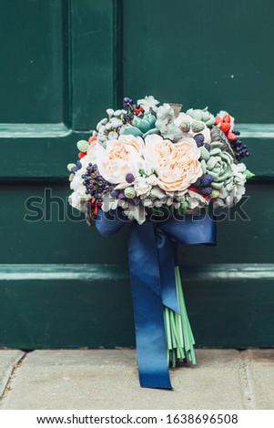 Handmade flowers made from Japanese polymer clay. They look like a real wedding bouquet. Against the background of a green wooden door