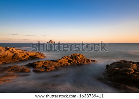 The island in the sea, the tide against the reef, the reef appears golden at dusk