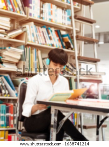 The blurry light design background of Young teenager wearing headphone on her head,reading and searching data from book,at library,blurry light around