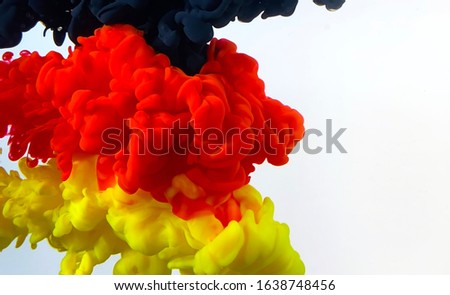 Germany flag made of color ink on a white background. Black, yellow and red watercolor ink in water. Stylish abstract modern background. A powerful explosion of colors. Cool trending screensaver.