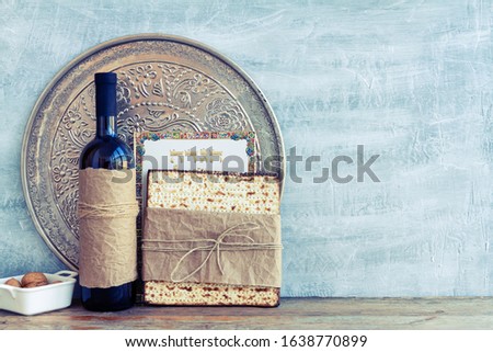 Metal plate with matzah or matza and Passover Haggadah on a vintage wood background presented as a Passover seder feast or meal with copy space. Translation: Passover Haggadah Royalty-Free Stock Photo #1638770899