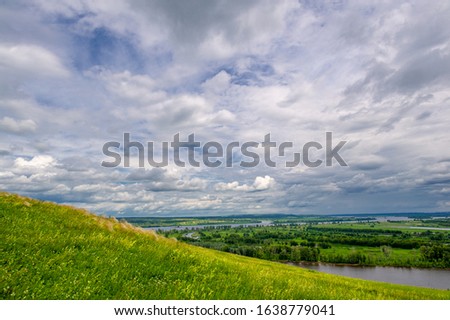 Summer landscape, a large full-flowing river, meadow flowers on the banks of the river, mighty clouds in the sky, a tourist walk along the Kama River