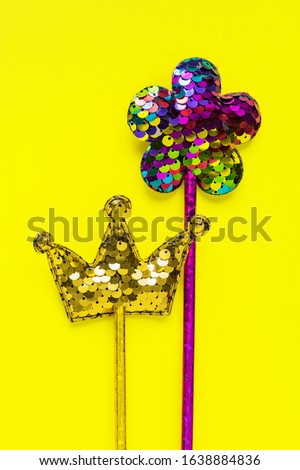 Golden crown and pink flower made of  round sequins on yellow background. Fashion party accessories  with copy space. Festive flat lay. Minimal style.