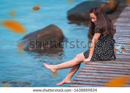 girl in black dress sitting by posing and relaxing on the walkway wood with smile happy in vacation trip and in sea view a happy holiday and happy time in vacation