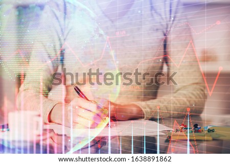 Hand taking notes in notepad. Forex chart holograms in front. Concept of research. Double exposure