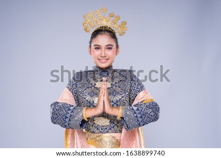 A beautiful Malaysian traditional female dancer with a charming smile performing a cultural dance steps in a traditional outfit. Half length isolated in grey.