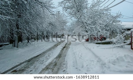 Snow covered residential street after a blizzard. Snowy landscape with covered by fresh snow street and trees. Small city life background. Beautiful winter morning after snowfall background.