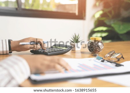 Businessman hands with calculator and cost at the office and financial data analyzing counting on wooden table.