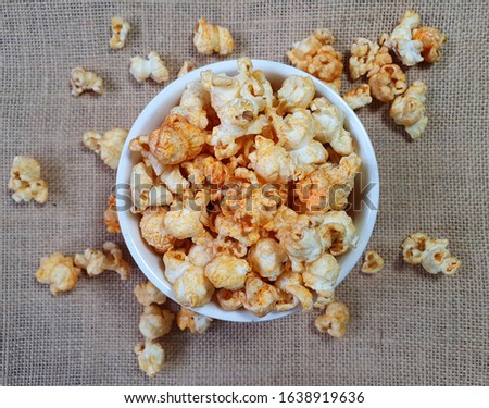 spicy popcorn in a white ceramic bowl on beige fabric background (selected focus at popcorn in the center of picture)