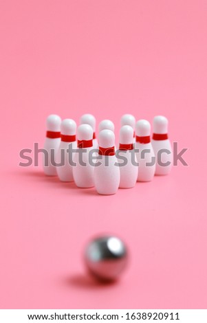 Closeup of a wooden mini bowling game set and pins on pink background