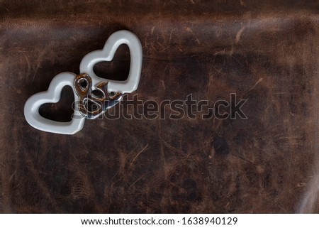 Valentine's day, two white hearts and And You symbols on leather background. High angle view, space for text.