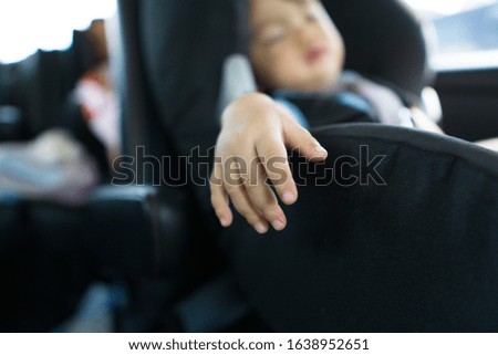 Close-up picture of a baby's hand sleeping comfortably in a car seat