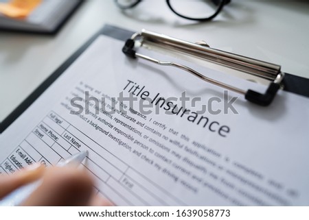 Woman Filling Title Insurance Form Over White Desk Royalty-Free Stock Photo #1639058773