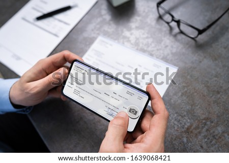 Man Taking Photo Of Cheque To Make Remote Deposit In Bank Royalty-Free Stock Photo #1639068421