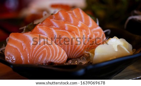 Salmon Sashimi, Raw salmon slice or salmon sashimi in Japanese style fresh serve on ice with pictures of pickled ginger. Japanese food concept.