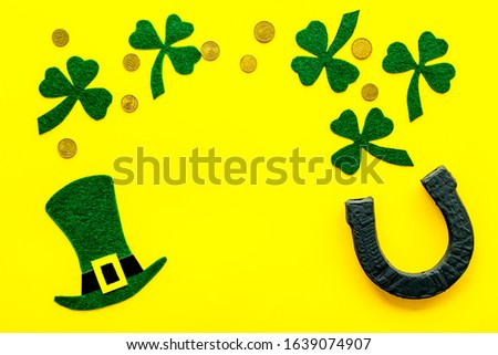 Composition for St. Patrick's Day.
Decorating paper with green clover or shamrocks, leprechaun hat and horseshoe.
Yellow background top view,flat lay, mockup