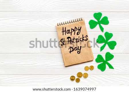 Composition for St. Patrick's Day.
Decorating paper with green clover or shamrocks, leprechaun hat and horseshoe.
White wooden background top view,flat lay, mockup