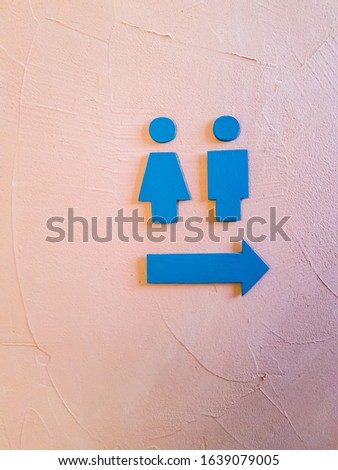 Toilet sign Loft style made from wood with male and female and arrow blue color on orange rough wall, background texture image.
