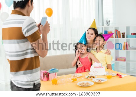 Image of a father making o photo of his family on the party on the foreground
