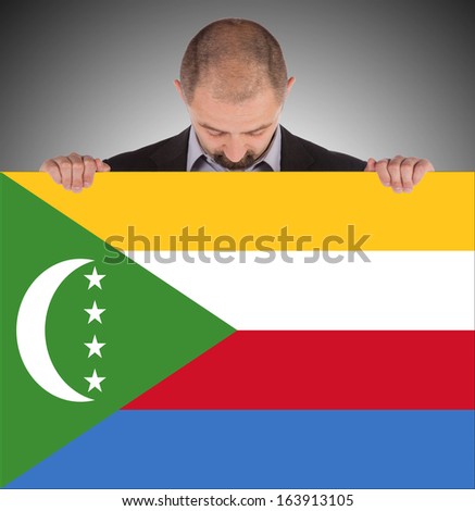 Smiling businessman holding a big card, flag of The Comoros