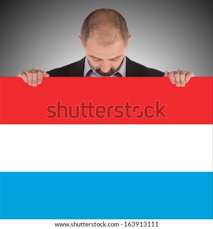 Smiling businessman holding a big card, flag of Luxembourg