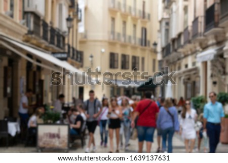 Purposely blurred photo of people walking on a pedestrian street with terraces and restaurants in historical center of european city