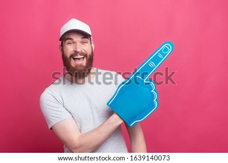 excited young happy man pointing away with fan foam glove