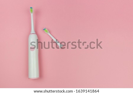 Electric toothbrush with a new head and a used one on a soft light pink background. Oral cavity home health care technology, medical concept. Copy space, top view