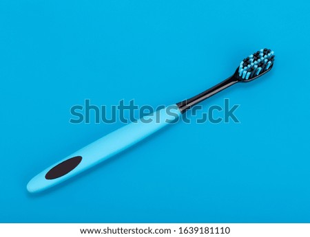 Blue-black toothbrush on a blue background. Oral health. Personal hygiene.