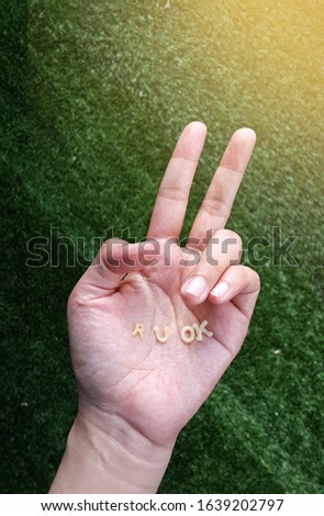 Hand show two fingers with alphabet pasta "R U OKI" on green grass background. Cheer up and positive thinking concept.