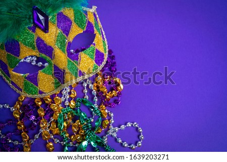 Colorful Mardi Gras mask on purple background with beads