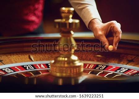 Hand of a croupier with a ball on a roulette wheel during a game in a casino. Royalty-Free Stock Photo #1639223251